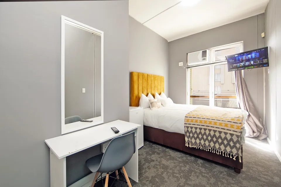 Private room with king-size bed, yellow headboard, desk and TV