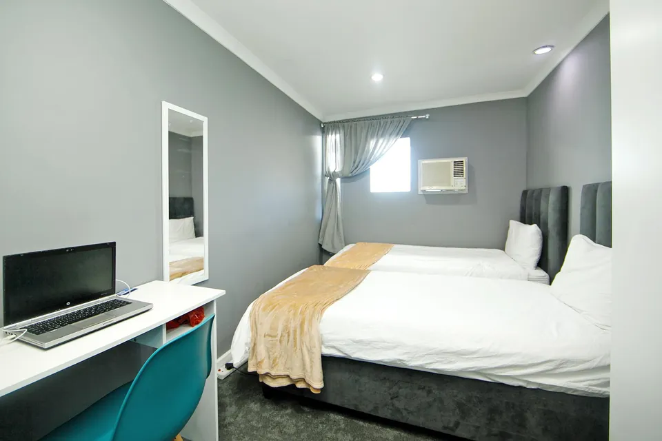 Twin-bed room with desk, laptop and mirror
