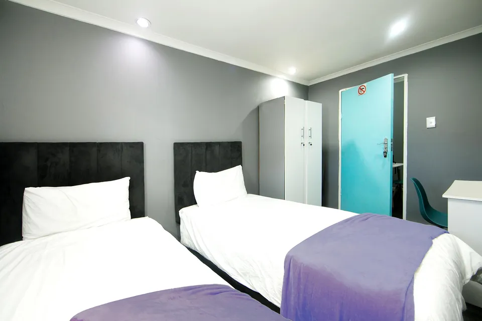 Two single beds with dark headboards and a turquoise door