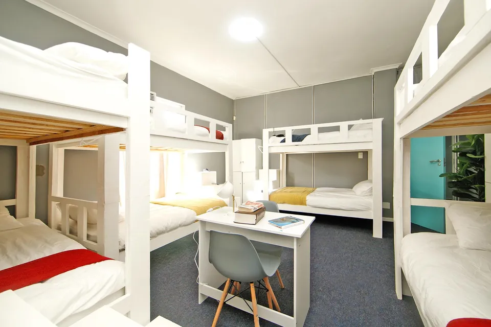 Bright dormitory with white bunk beds and a table
