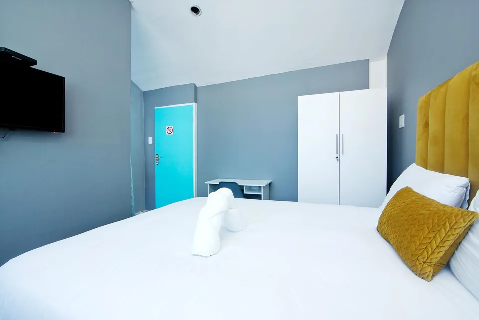 King-size bed with mustard cushion and a wall-mounted TV
